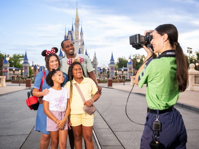 Familia con el castillo de Cenicienta de fondo mientras un fotógrafo de PhotoPass les toma una foto